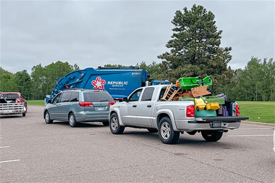 Vehicles line up waiting to drop off their items to be recycled/disposed. A blue Republic Services truck sits in the background.