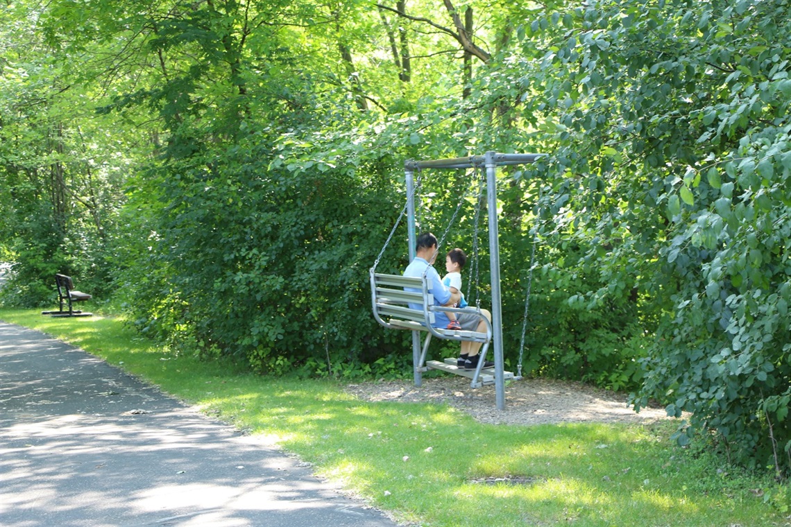 A man and child sitting on a bench in a park
