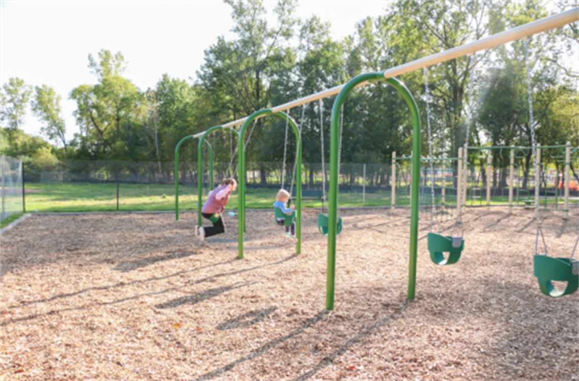 Adult and child swing on the swings